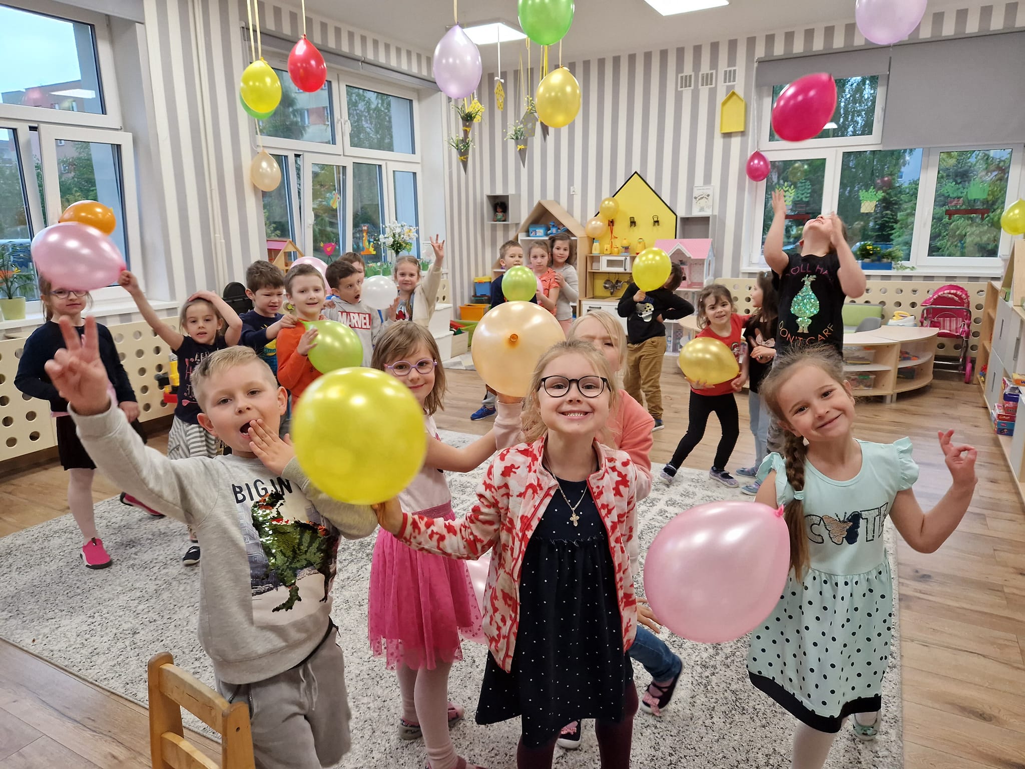 Dzieci bawią się balonami w sali przedszkolnej